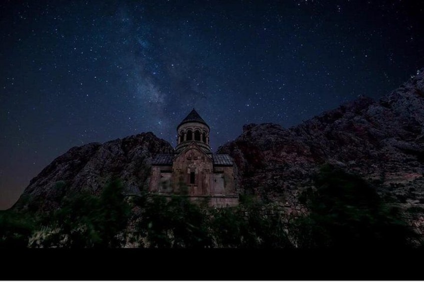 Una montaña con un pequeño edificio, posiblemente una capilla, bajo un cielo estrellado. 3