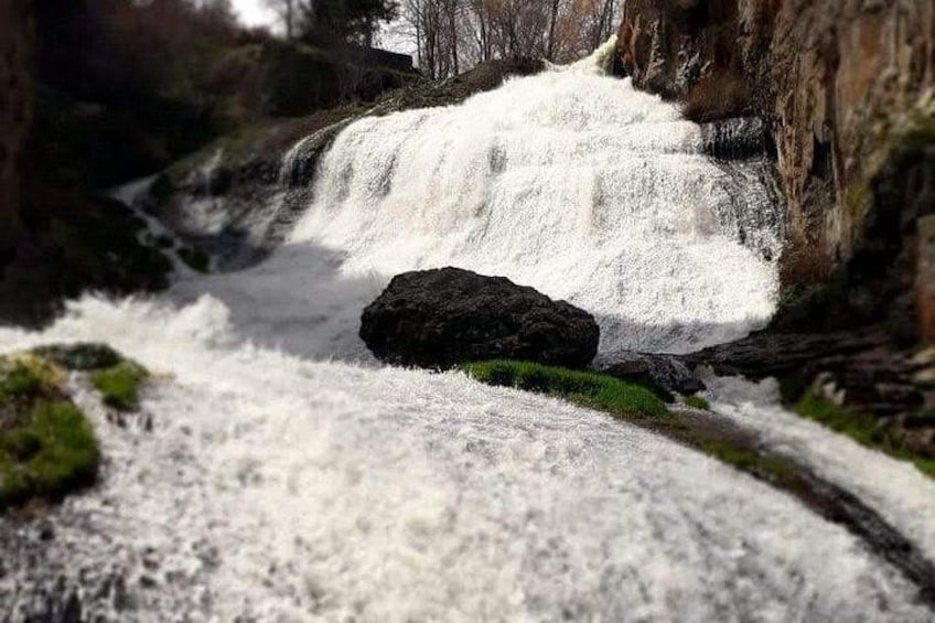 Una cascada que se precipita sobre rocas en una zona boscosa. 2