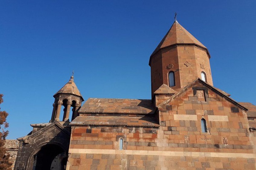 Una iglesia histórica con una imponente torre campanario y una estructura más pequeña contigua. 1