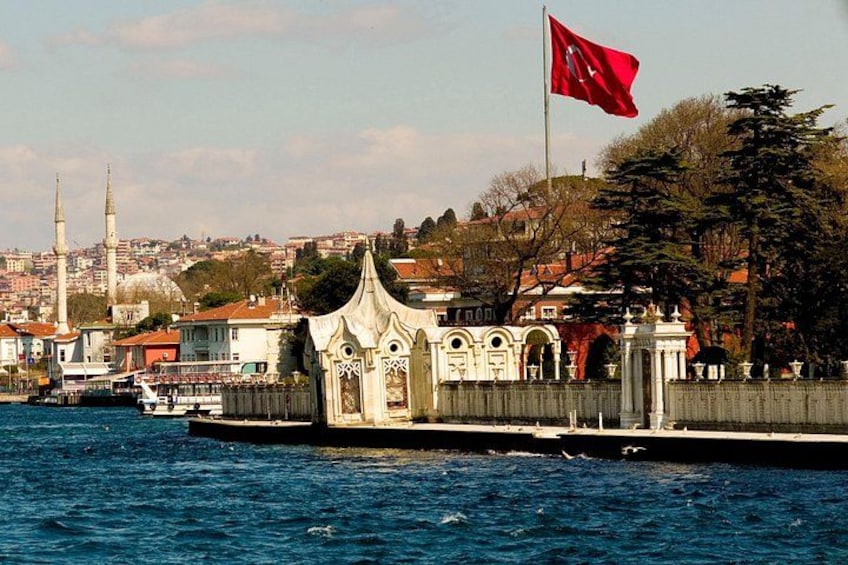 A waterfront view with a mosque, a flag, and a bridge. 1