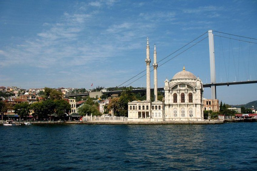 A mosque with two minarets and a dome, located near a bridge and water. 5