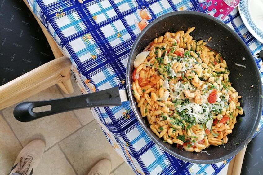 A pan of pasta with tomatoes and herbs on a checkered tablecloth. 3