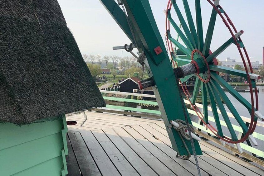 A wooden deck with a thatched roof structure and a large green and red wheel structure. 1
