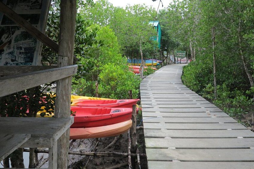 A wooden boardwalk with kayaks and a green structure in the background. 2