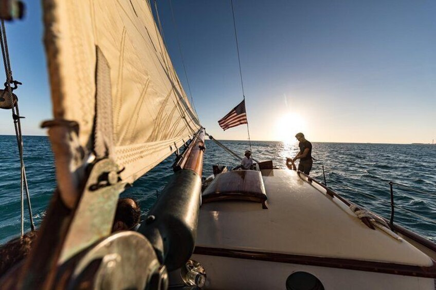 A sailboat with an American flag, sailing on the ocean during the day. 2