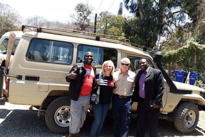 A group of people standing in front of a beige off-road vehicle. 2