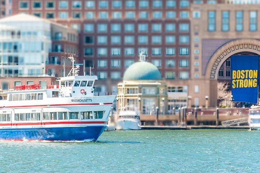 Un letrero que dice 'Boston Strong', un barco grande azul y blanco, y un edificio con una cúpula. 2