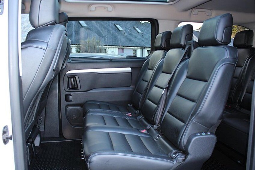 A vehicle interior with black leather seats, a sunroof, and a rearview mirror. 2