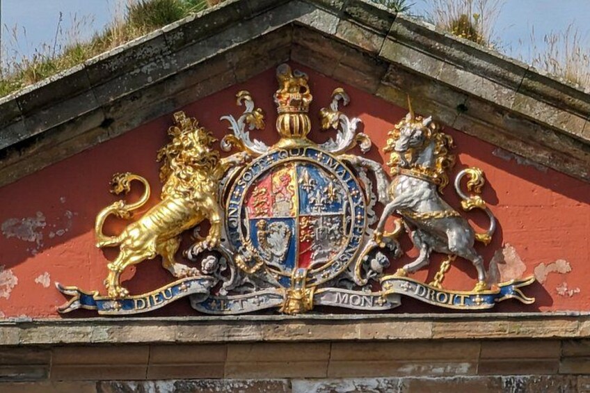 A heraldic coat of arms with lions and a crown on a red wall. 5