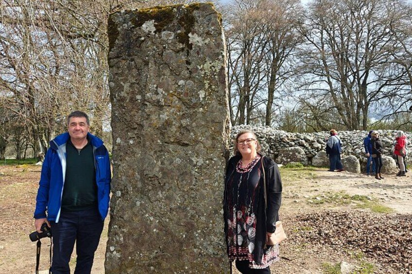 A stone structure, a person with a camera, and a group of people in a natural setting. 2