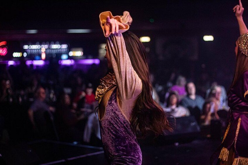 A person in a purple dress with gold details, holding a phone. 1