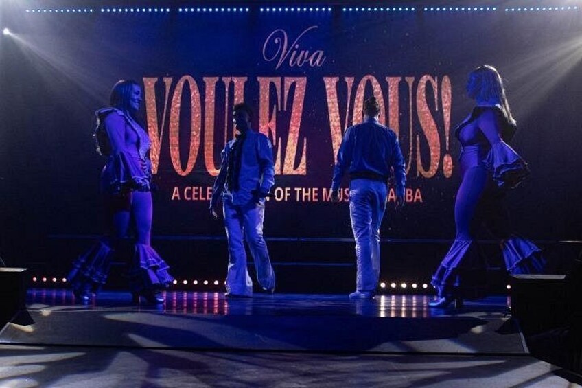 A stage with a large sign reading 'Viva VOLEZ VOUS!' and performers in the background. 2