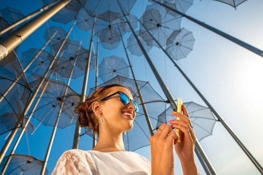 A person holding an umbrella, standing under a structure with multiple umbrellas. 3