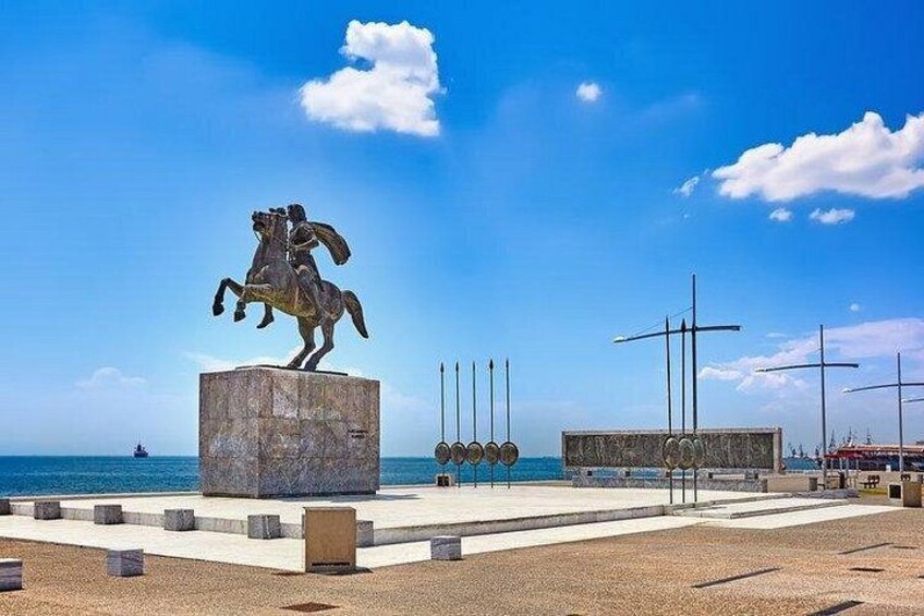A statue of a man on horseback, a pier with a ship in the background, and a clear blue sky. 2