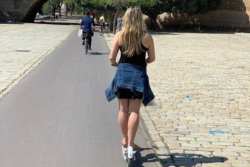 Une personne marchant sur un chemin pavé, un cycliste en arrière-plan et un sol recouvert de pavés. 4