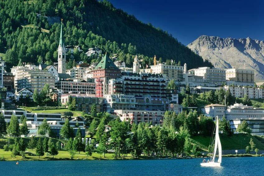 Une ville au bord d’un lac, avec des bâtiments, une église et un voilier. 4