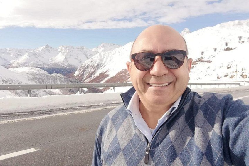 A person standing on a road with snow-covered mountains in the background. 3