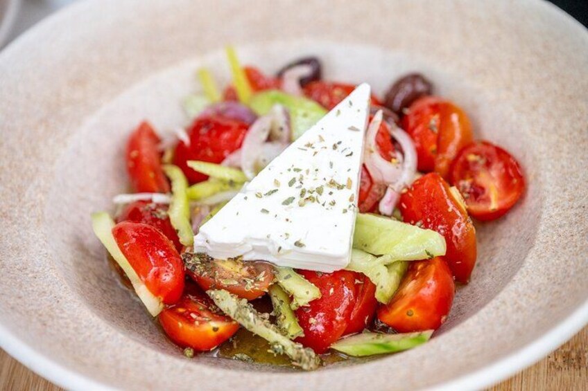A plate of Greek salad with tomatoes, cucumbers, onions, and feta cheese. 2