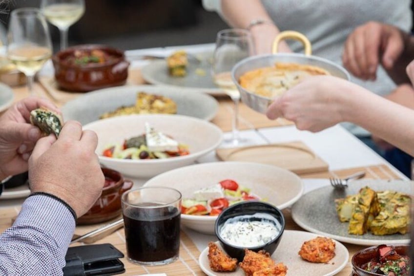 A group of people dining at a table with various dishes, glasses of wine, and a bottle of soda. 5