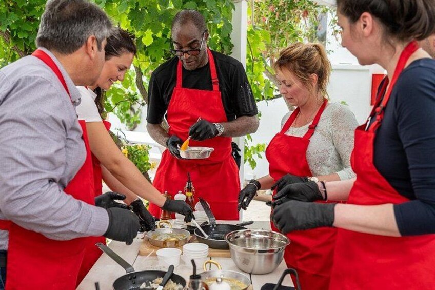 Eine Gruppe von Personen in roten Schürzen bereitet Essen im Freien zu. 1