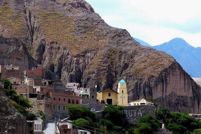 Una cittadina immersa in una valle, con una chiesa imponente e montagne sullo sfondo. 1