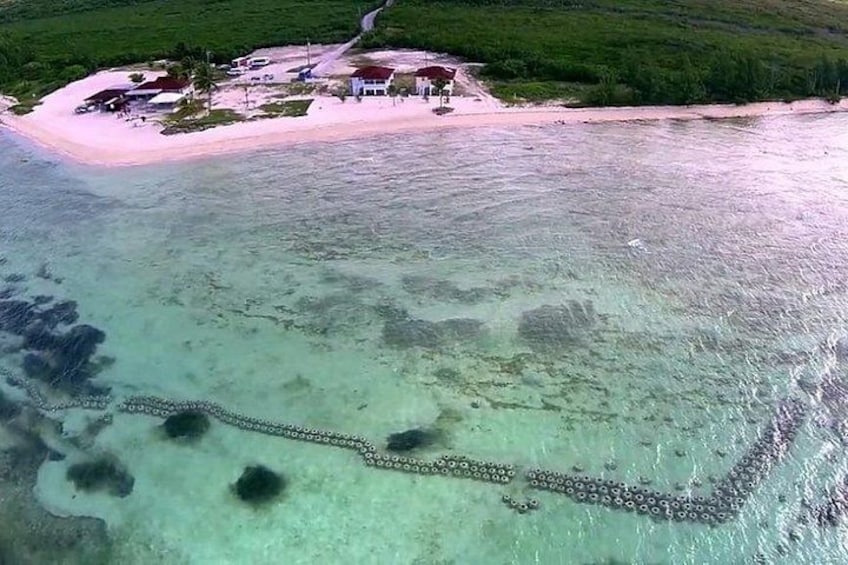 A coastal area with a clear waterway, a small island with buildings, and a sandy beach. 1