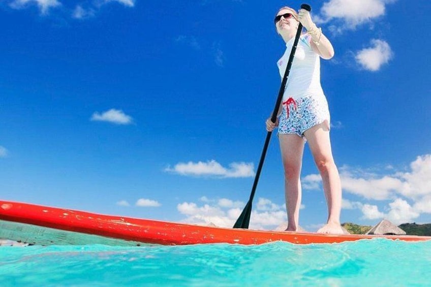 A person paddleboarding on turquoise water with a clear blue sky. 2