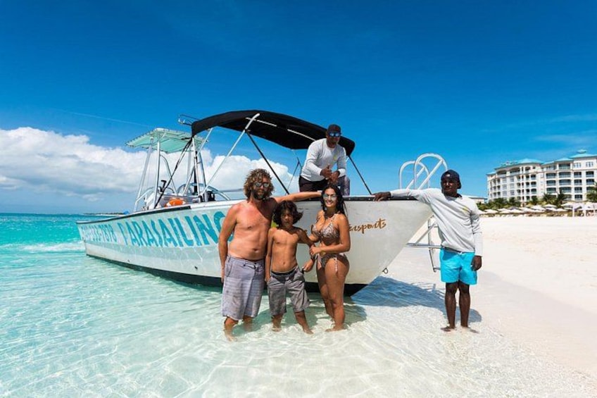 Un barco llamado 'Paraisalining' en una playa con agua turquesa cristalina, una orilla de arena blanca y un hotel al fondo. 2