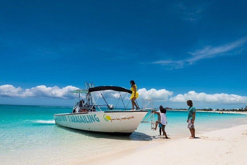 A boat named 'PIRATA FARAKALING' on a beach with clear turquoise water and a clear sky. 5