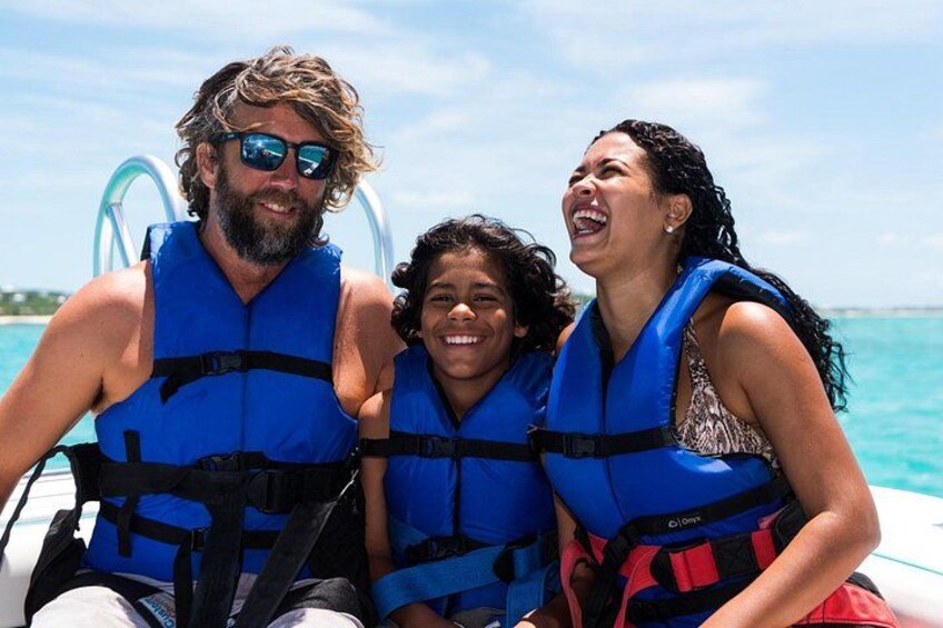 Three people on a boat wearing blue life jackets. 3