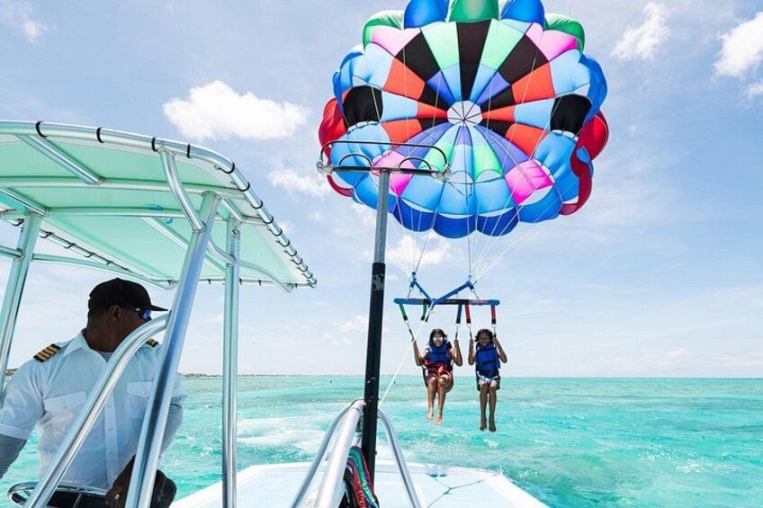 Actividad de parasailing con un paracaídas colorido, un bote y un mar azul cristalino. 5