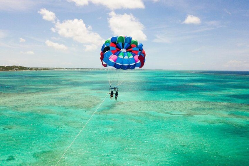 A person parasailing over turquoise waters with a colorful parachute. 3