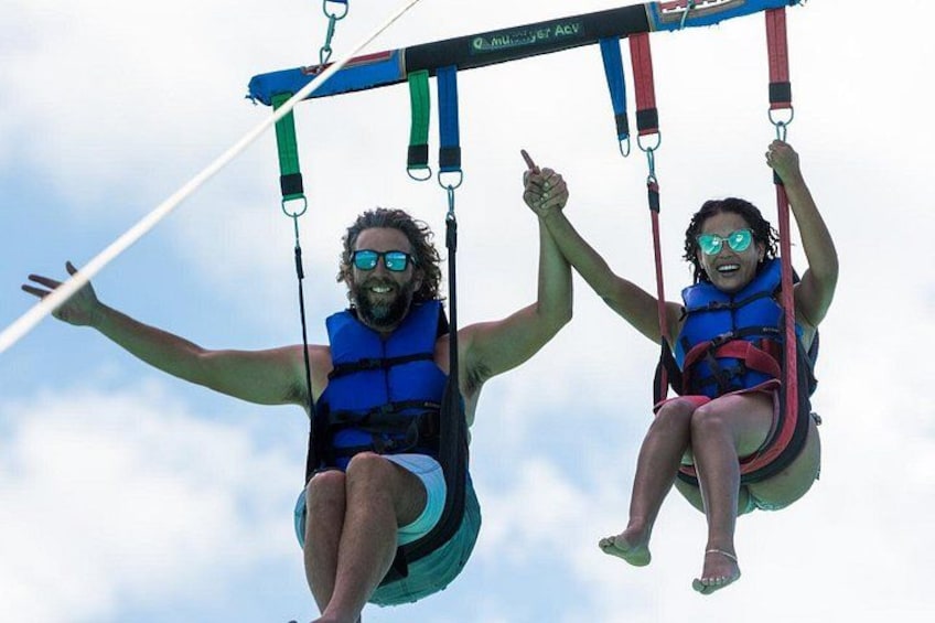 Two people on a swing ride, wearing life jackets and holding onto the bars. 1