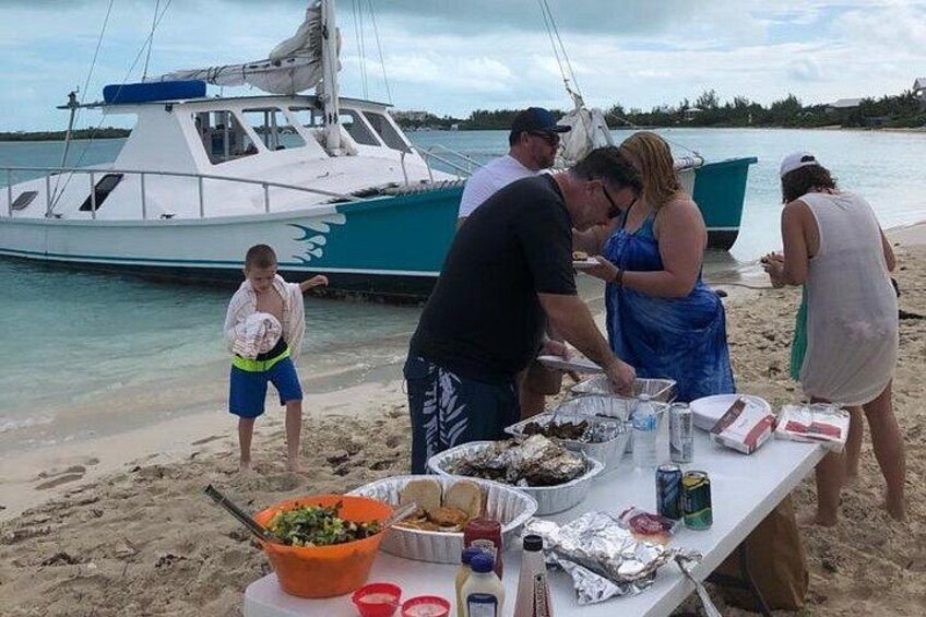 Un grupo de personas preparando comida en una playa, con un bote al fondo. 3