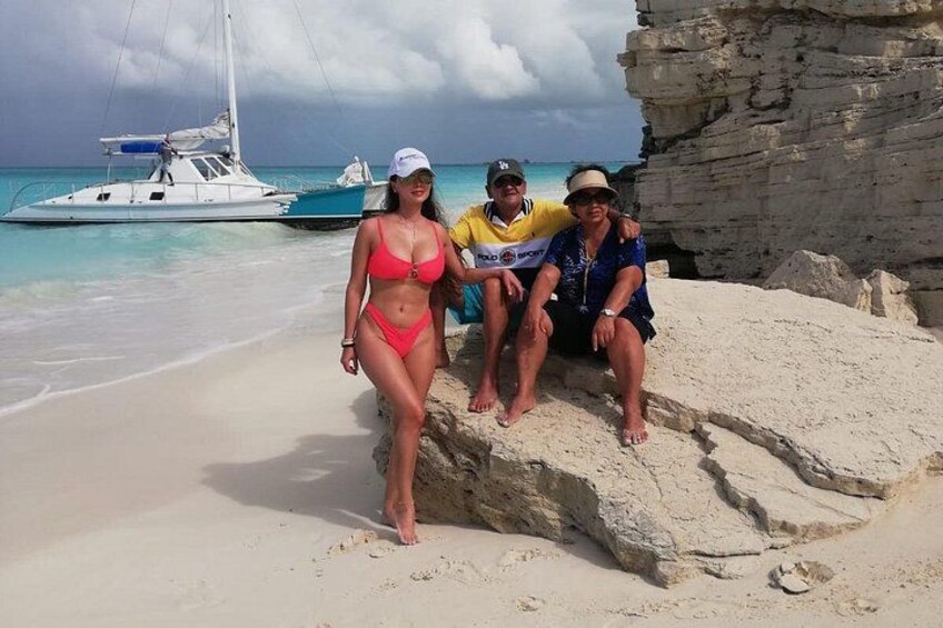 Una playa con un afloramiento rocoso, un barco en el agua y un cielo despejado. 4