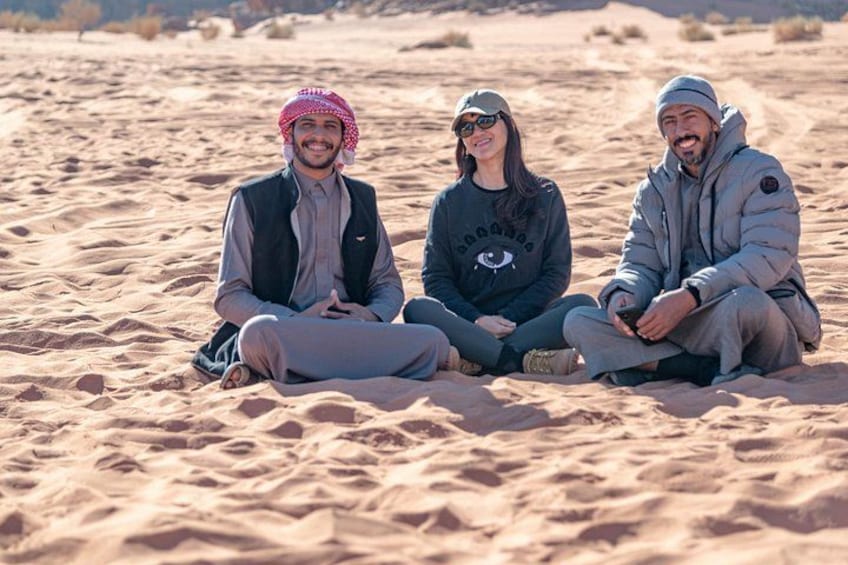 Three people sitting on a sandy beach. 3