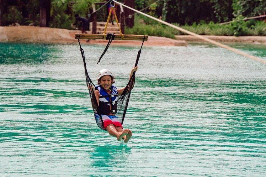 A person swinging on a rope swing over water. 2