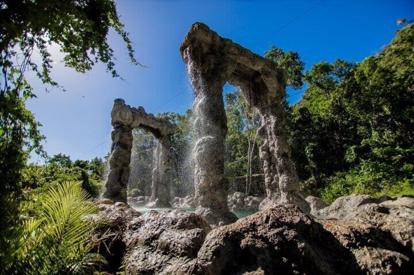 A natural rock formation with a cave-like structure and water flowing over it. 2