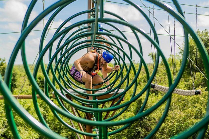 A person navigating a series of green loops suspended above a forested area. 5