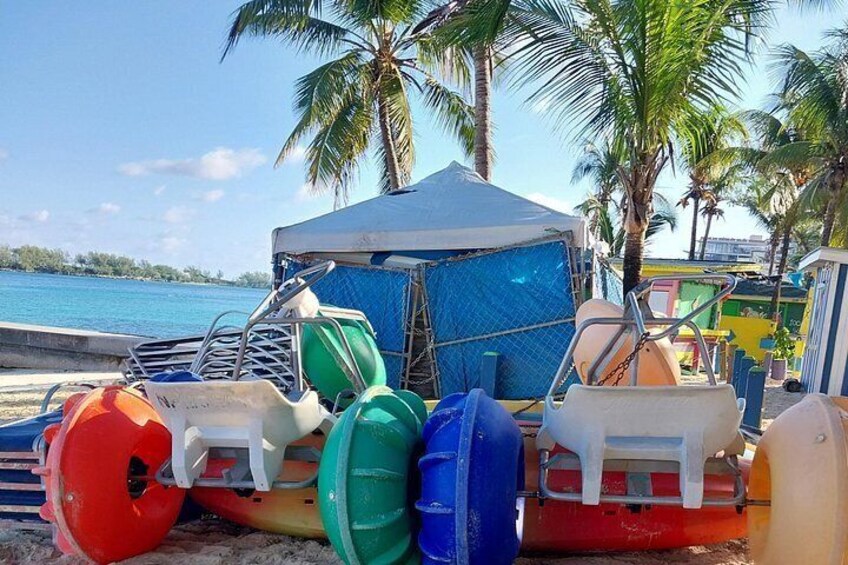 A beach with a blue tent, colorful buoys, and palm trees. 2