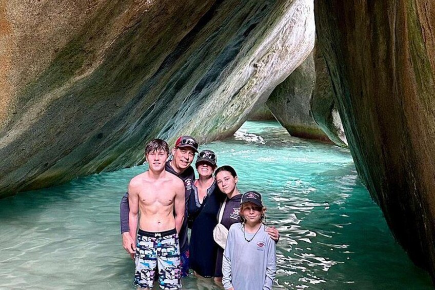 Un grupo de personas de pie frente a una formación rocosa natural con agua cristalina alrededor. 5