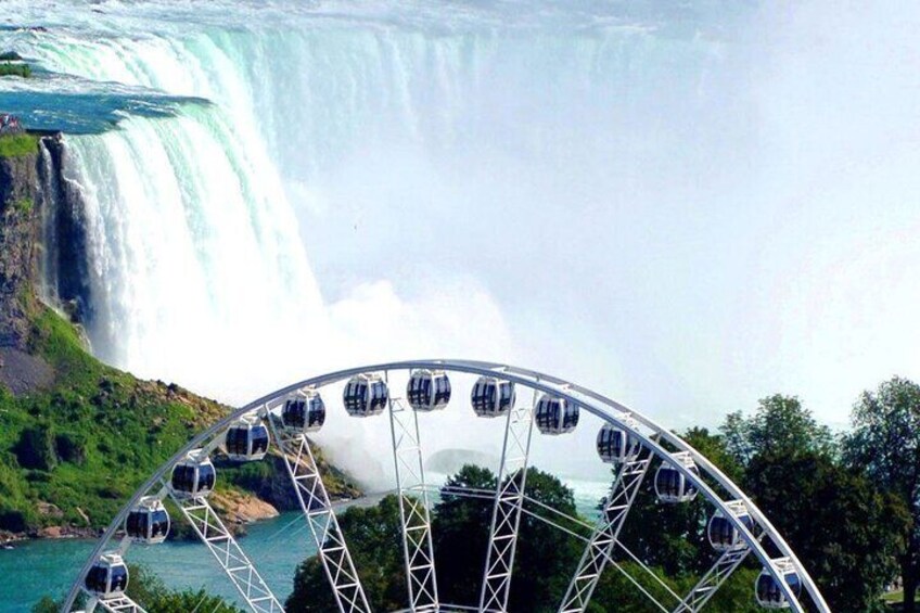 A Ferris wheel with gondolas in front of a waterfall. 3