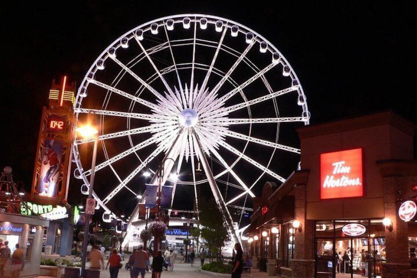 A large Ferris wheel at night with a Tim Hortons restaurant nearby. 2