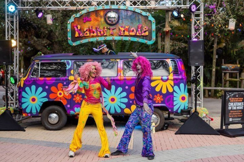 A colorful van with a sign reading 'The Rabbit Hole' and a stage setup with speakers and lights. 2