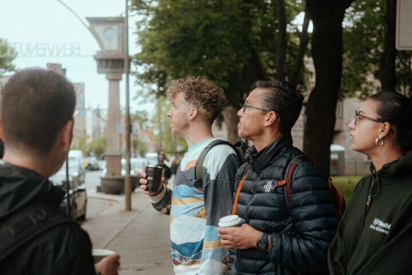 Three people standing on a sidewalk, holding coffee cups. 5