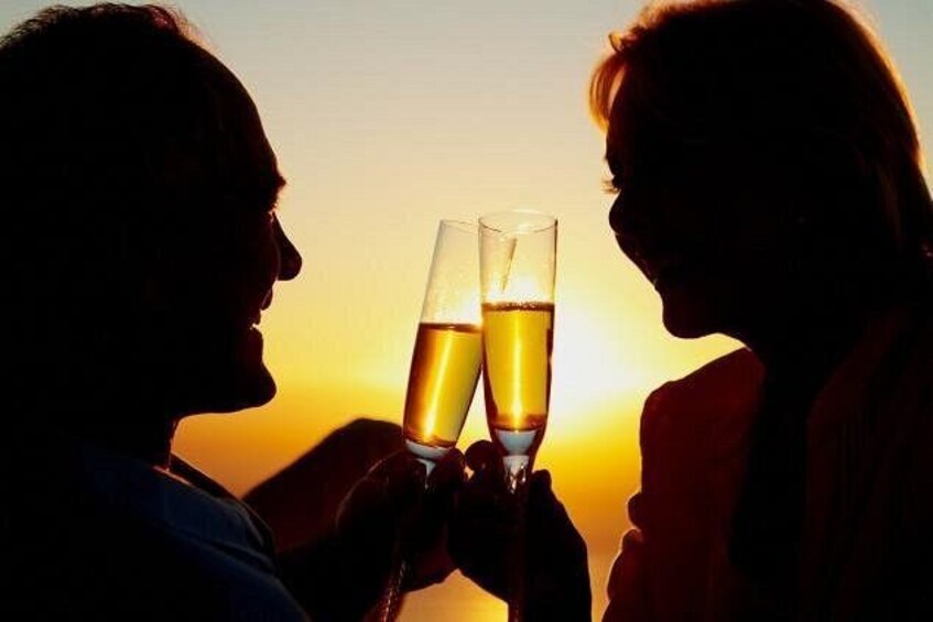 Two people toasting with champagne glasses against a sunset. 3