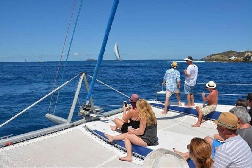 A sailboat with people on deck, a clear blue sky, and calm sea. 2