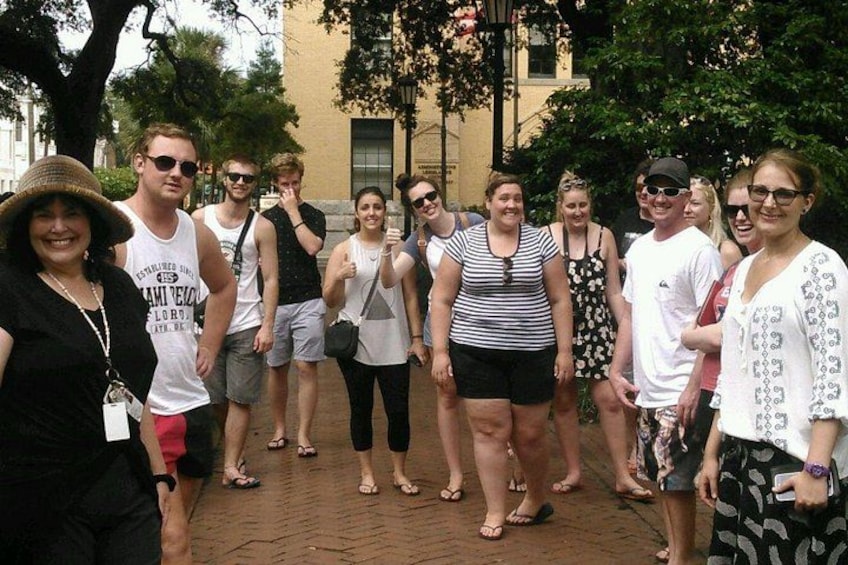 A group of people standing on a brick pathway with trees and a building in the background. 1