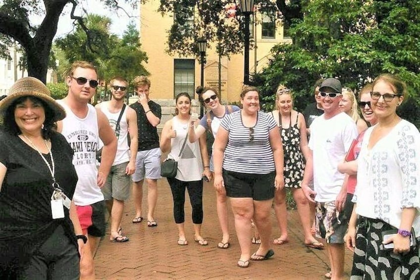 A group of people standing on a brick pathway with trees and a building in the background. 5