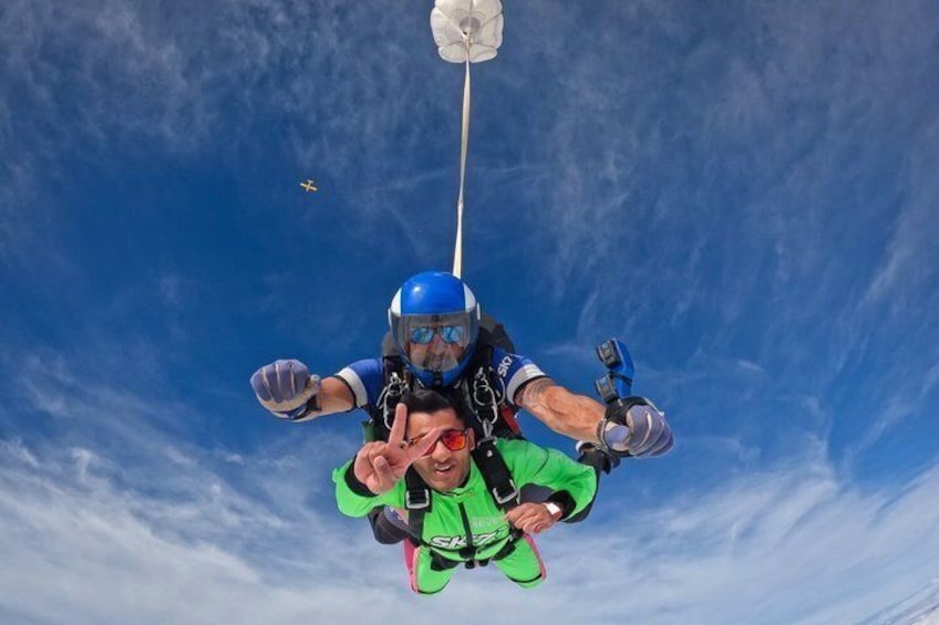 A person skydiving with a parachute, wearing a helmet and goggles, and a green jumpsuit. 5